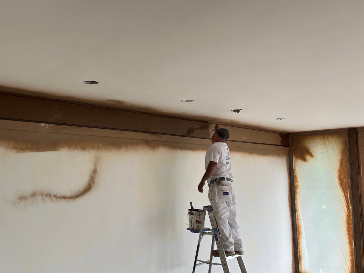 A PDS Painting & Drywall Specialists crew member cutting in a ceiling line during an interior repaint
